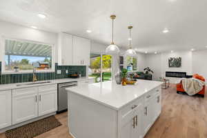 Kitchen with white cabinets, a large fireplace, open floor plan, decorative backsplash, and a textured ceiling