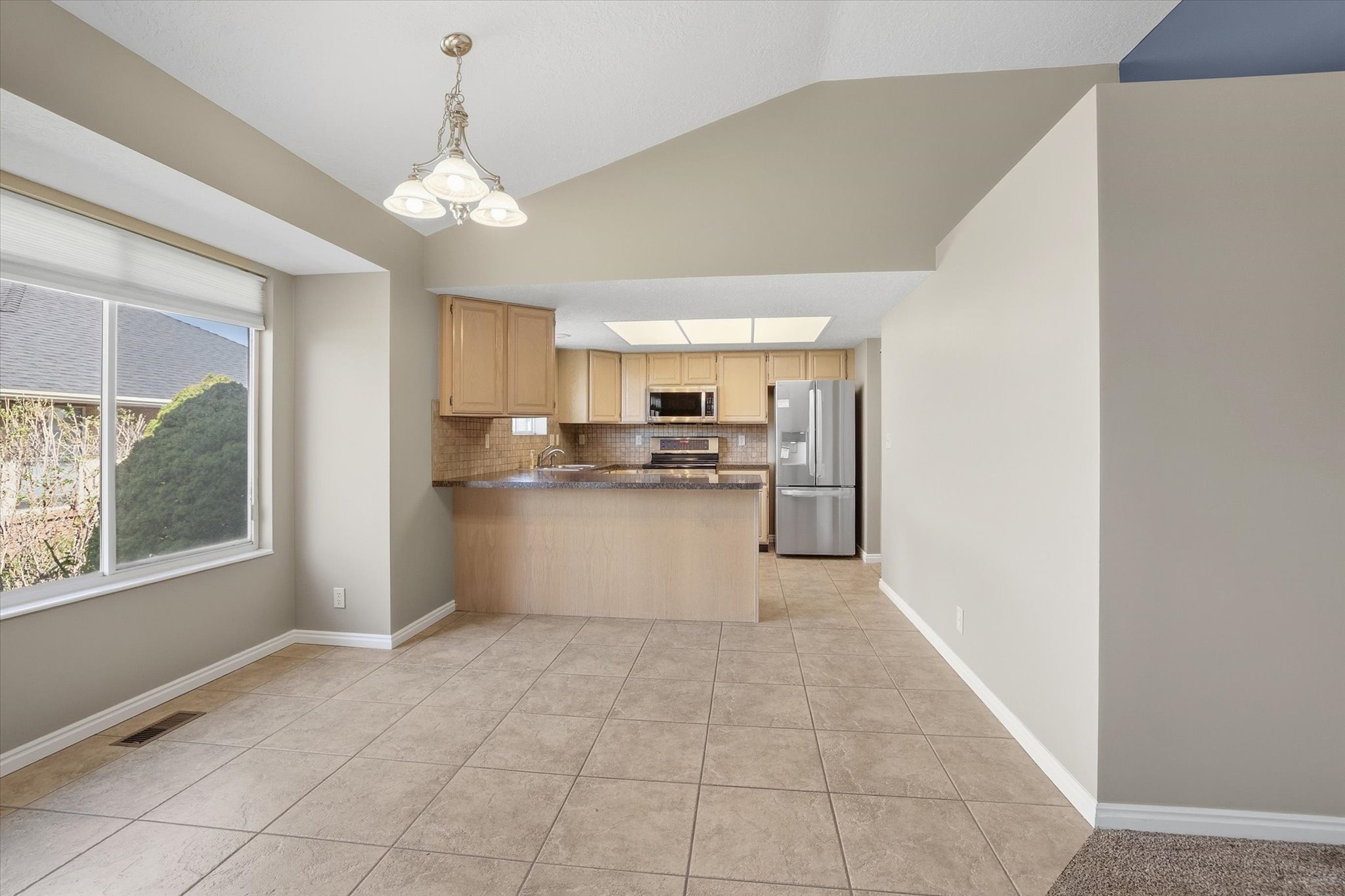 Kitchen featuring stainless steel appliances, backsplash, a peninsula, wood finish cabinets, and tiled floor