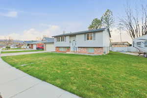 Bi-level home with brick siding, concrete driveway, and a chimney