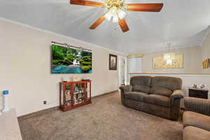 Carpeted living area with ceiling fan, a textured ceiling, ornamental molding, and suspended lighting
