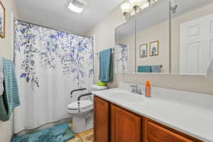 Bathroom with vanity, shower / bathtub combination with curtain, light tile patterned floors, and a textured ceiling