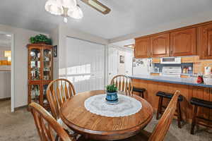 Dining area featuring light carpet, a textured ceiling, and ceiling fan