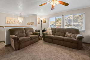 Living room with a ceiling fan, carpet floors, a textured ceiling, crown molding, and suspended lighting