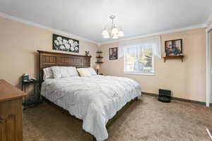 Carpeted bedroom with crown molding, suspended lighting, and a textured ceiling