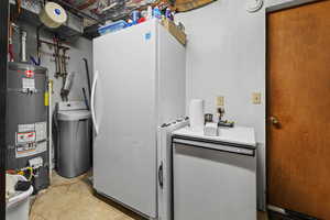 Laundry room with strapped water heater and unfinished concrete floors
