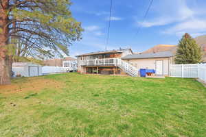 Rear view of house with a deck, a fenced backyard, a patio area, and a shed
