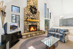 Carpeted living area featuring vaulted ceiling and a fireplace