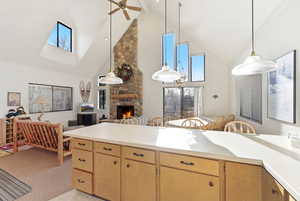 Kitchen featuring light countertops, a stone fireplace, open floor plan, and plenty of natural light