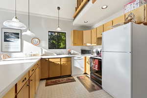 Kitchen featuring white appliances, light countertops, light floors, ornamental molding, and pendant lighting