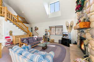 Carpeted living area with a fireplace, crown molding, and lofted ceiling