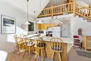 Kitchen with electric stove, freestanding refrigerator, pendant lighting, light countertops, and a peninsula