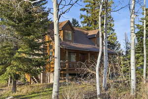 View of property exterior featuring log veneer siding, covered porch, and a shingled roof