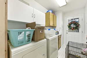 Laundry area with separate washer and dryer, light floors, and cabinet space
