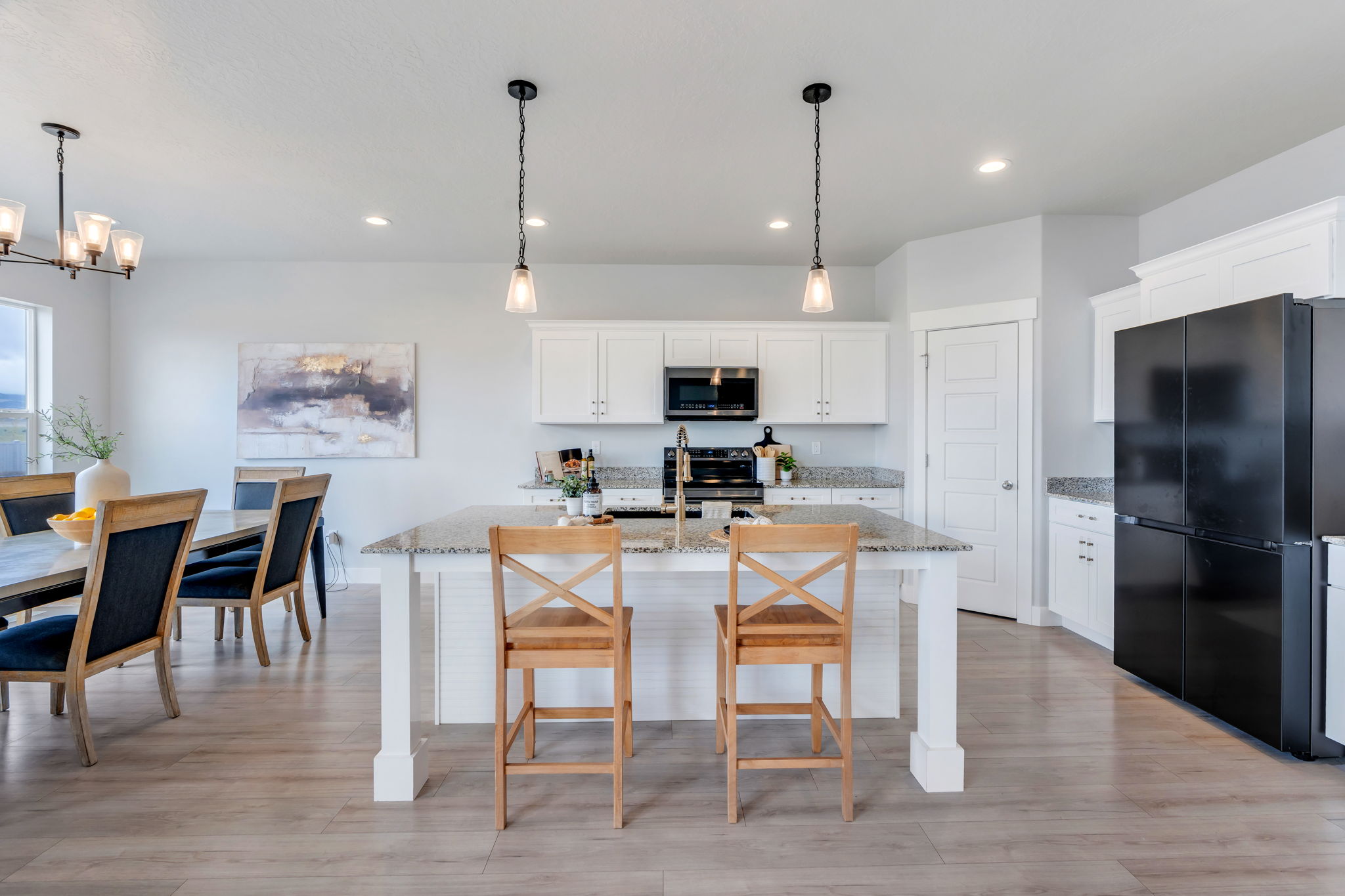 Kitchen featuring freestanding refrigerator, white cabinets, light stone countertops, and light wood finished floors