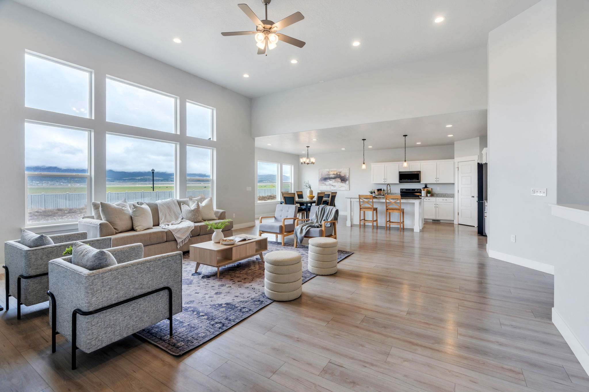 Living area with ceiling fan, light wood-type flooring, a high ceiling, and recessed lighting
