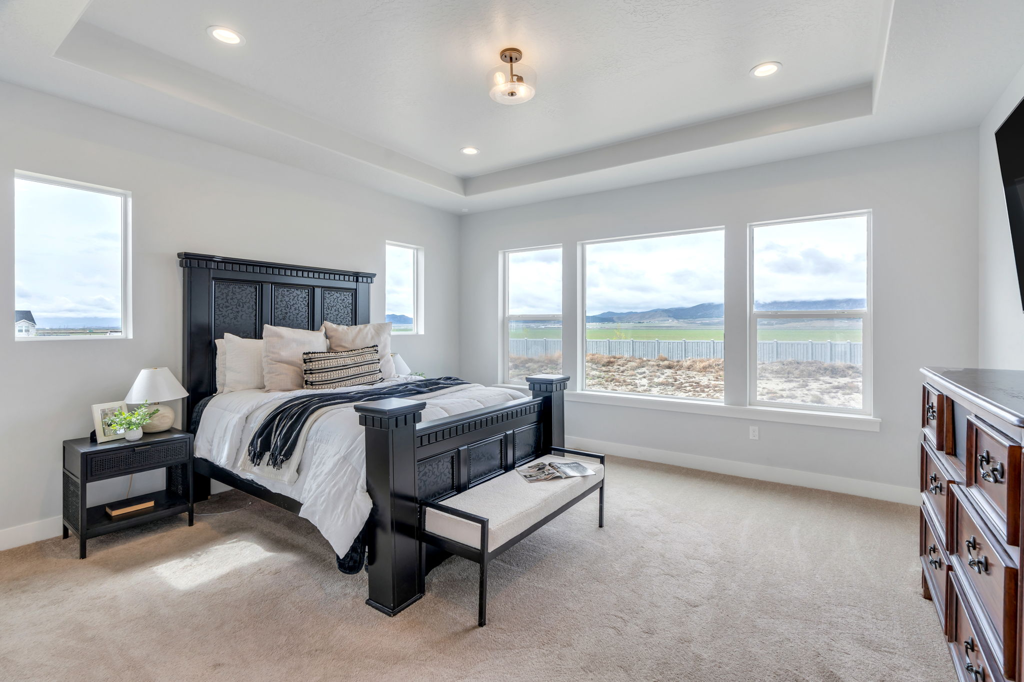 Bedroom with light colored carpet, recessed lighting, and a tray ceiling