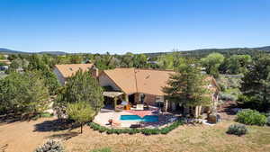 Rear view of house with a tiled roof, a patio area, an outdoor pool, a pergola, and a chimney