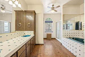 Full bathroom featuring a ceiling fan, vanity, a shower stall, light wood-style flooring, and a bath