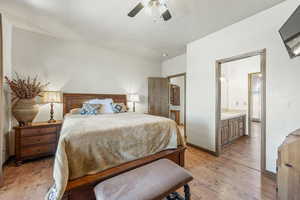 Bedroom featuring light wood-style floors, a ceiling fan, and ensuite bath
