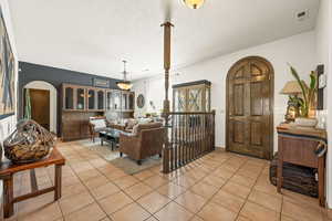 Living room with arched walkways, light tile patterned flooring, and a textured ceiling