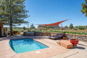 View of swimming pool with a fenced backyard, patio surround, and a hot tub
