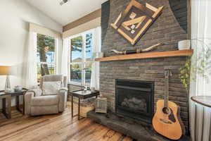 Sitting room featuring vaulted ceiling, a brick fireplace, and hardwood / wood-style floors
