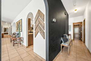 Corridor featuring light tile patterned floors, arched walkways, and a textured ceiling