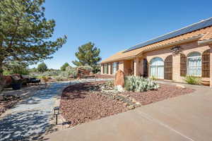 View of property exterior featuring brick siding, solar panels, and a tiled roof