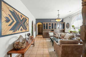 Living room featuring arched walkways, light tile patterned flooring, and a textured ceiling