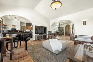 Living room featuring arched walkways, wood finished floors, lofted ceiling, and ceiling fan