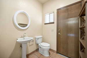 Half bath featuring toilet and light tile patterned flooring