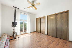 Unfurnished bedroom with two closets, light wood-style floors, and a ceiling fan