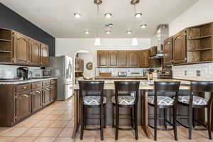 Kitchen with open shelves, backsplash, and arched walkways