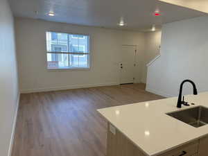 Kitchen with light wood-style flooring, light stone counters, and open floor plan