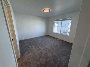 Empty room featuring dark colored carpet and baseboards
