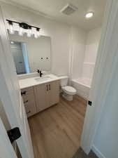 Full bathroom with vanity, light wood finished floors, and washtub / shower combination