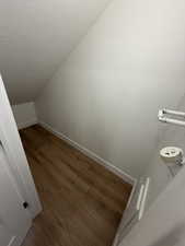 Stairway with wood finished floors and a textured ceiling