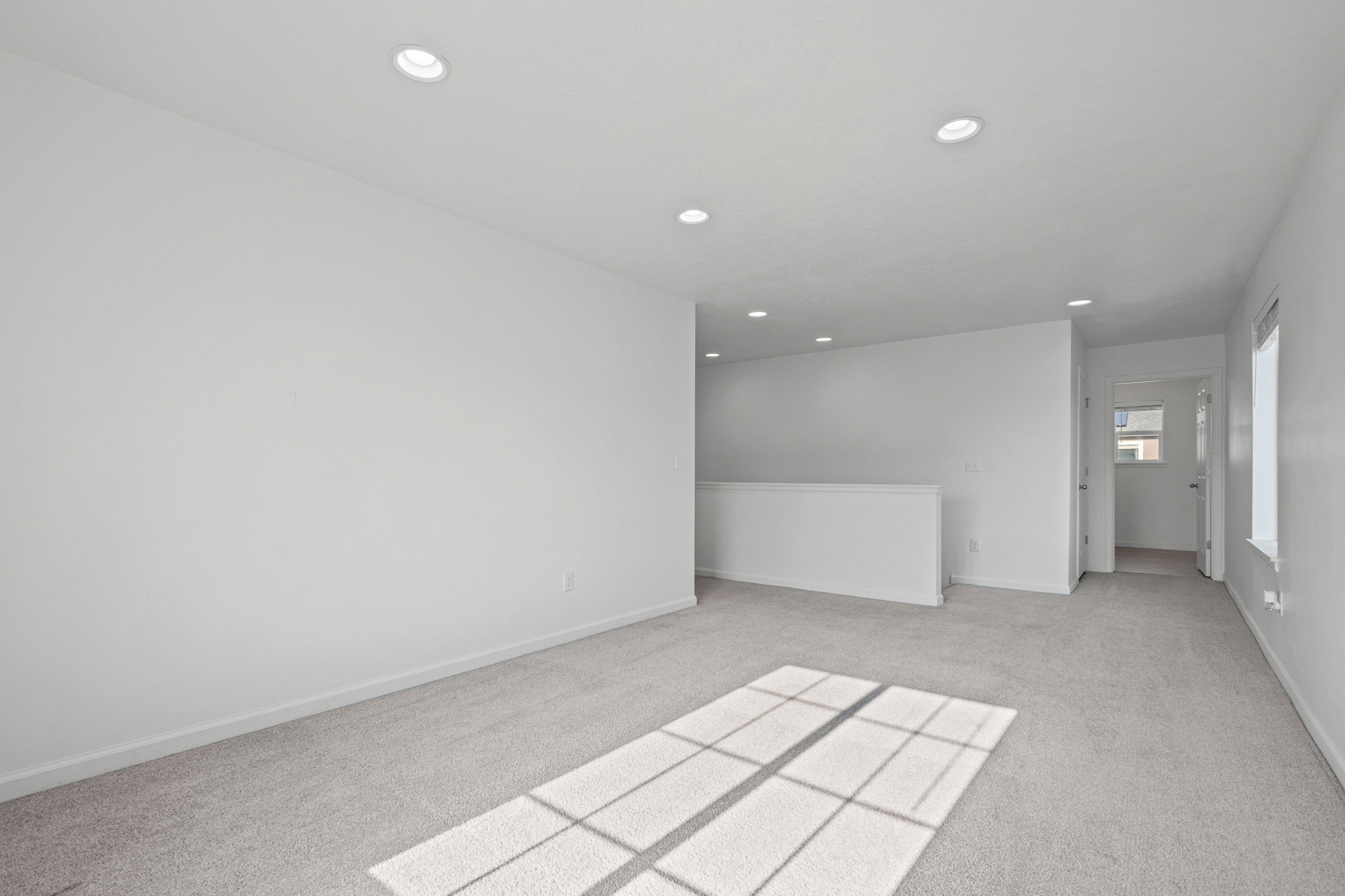 Spacious room featuring neutral carpeting, white walls, and recessed lighting