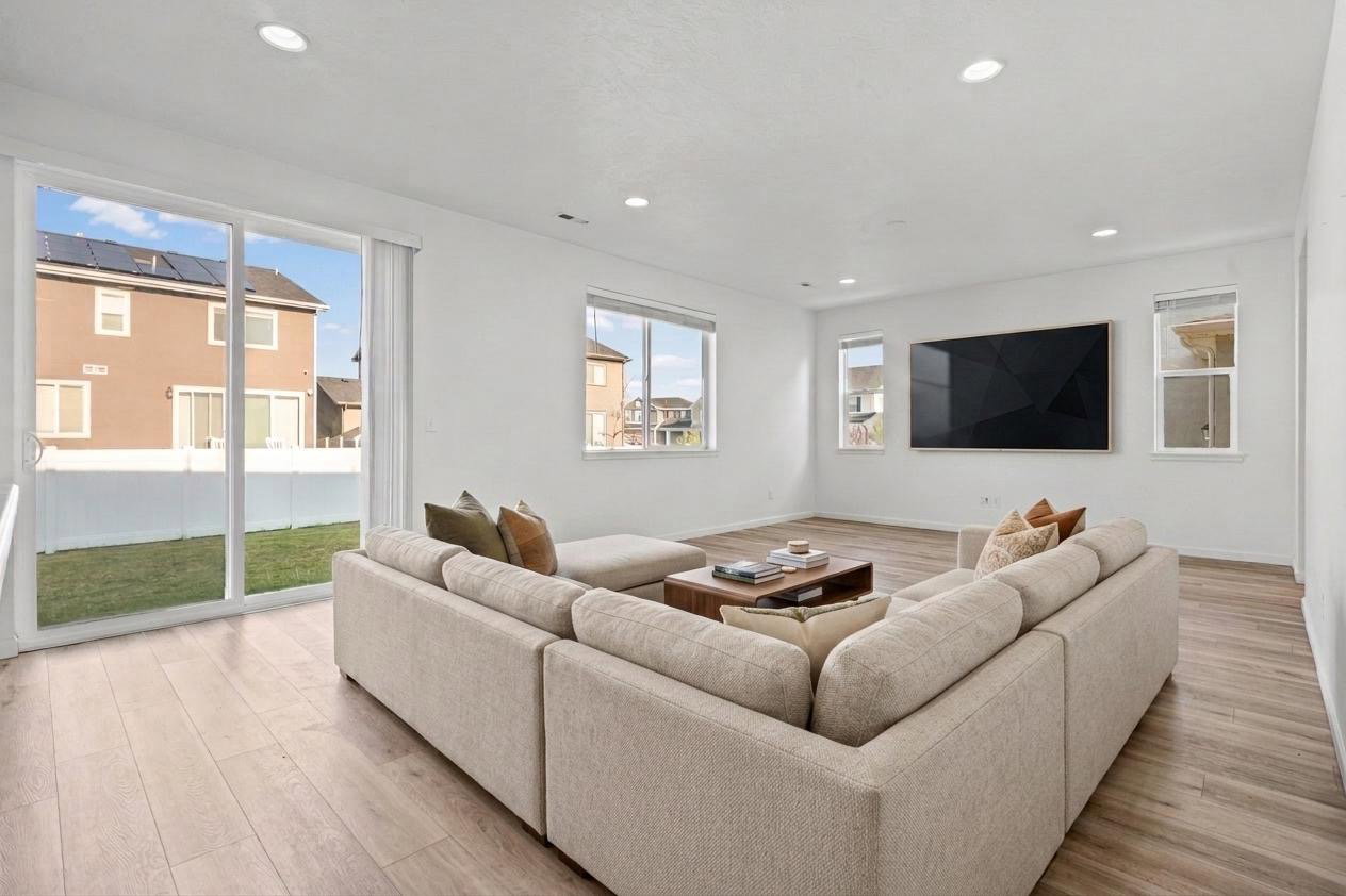 Spacious living area featuring wood-finish flooring, recessed lighting, and white wallsVirtually Staged