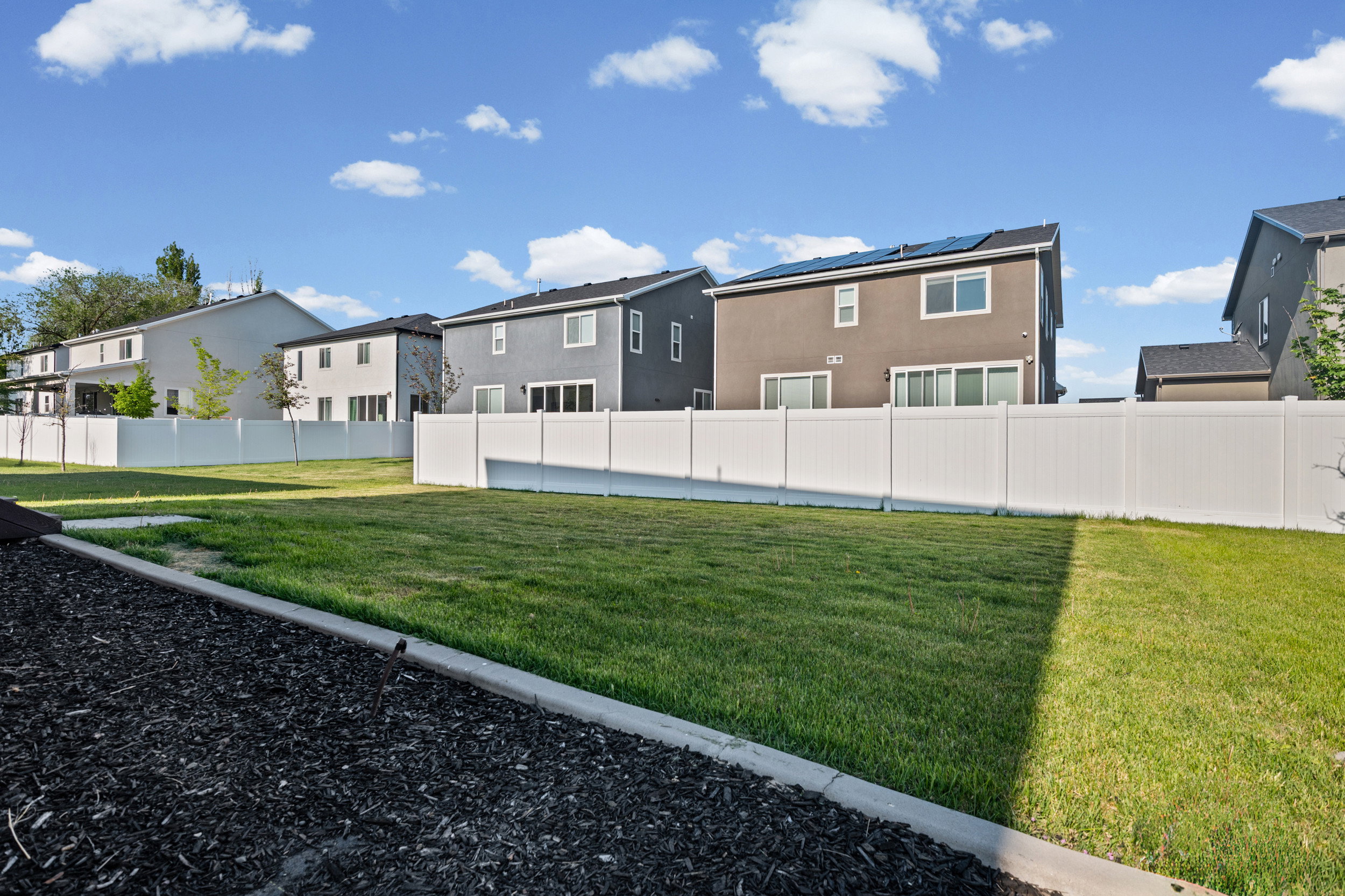 Expansive grassy area bordered by a white vinyl fence