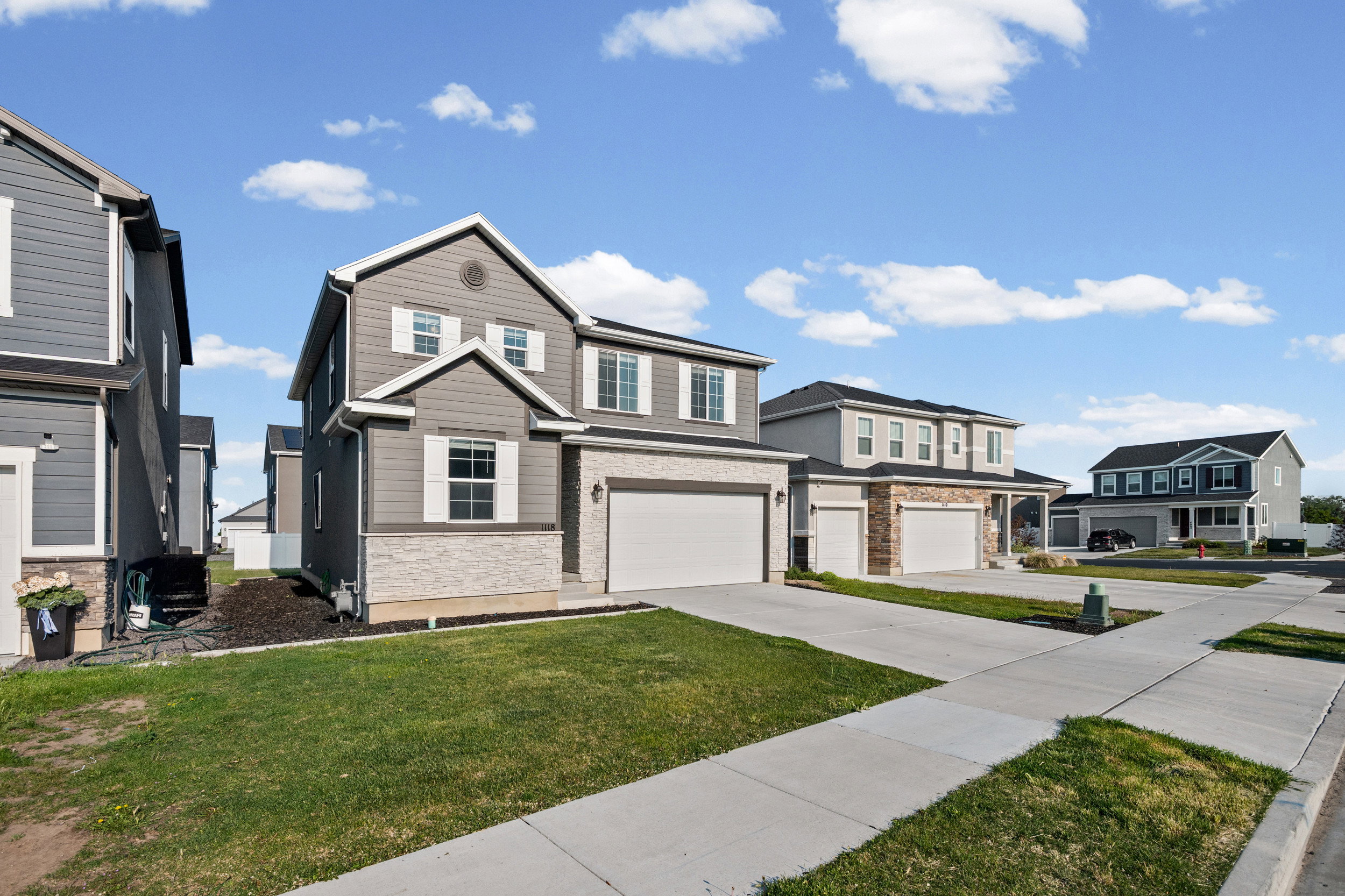 Two-story residence featuring grey siding and light-colored stone accents