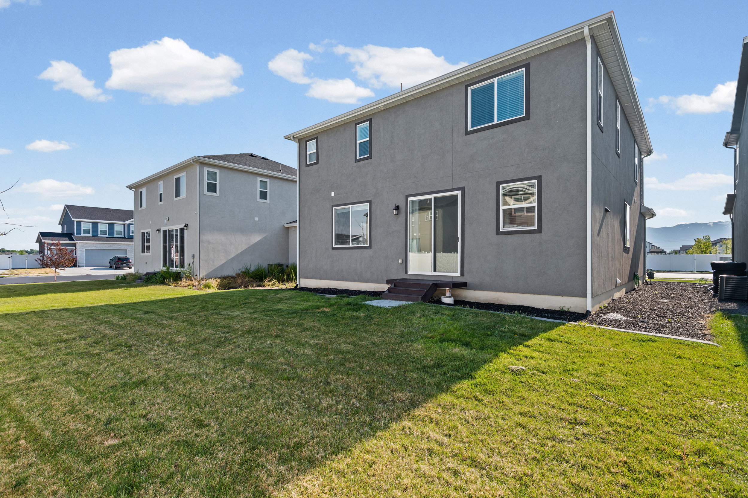 Expansive grass yard with a two-story stucco exterior