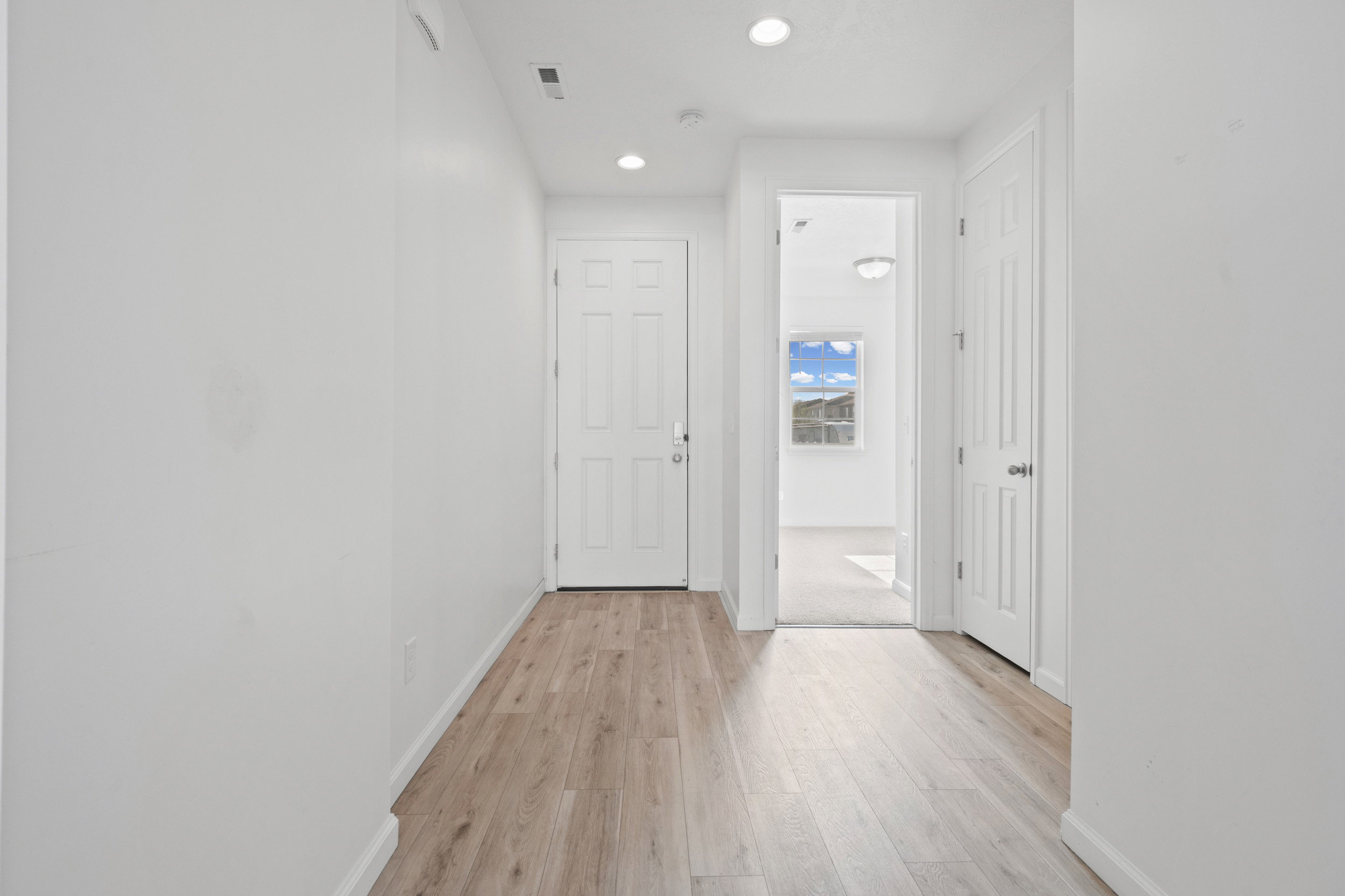 Entryway featuring wood-finish flooring, white paneled doors, recessed lighting, and white baseboards