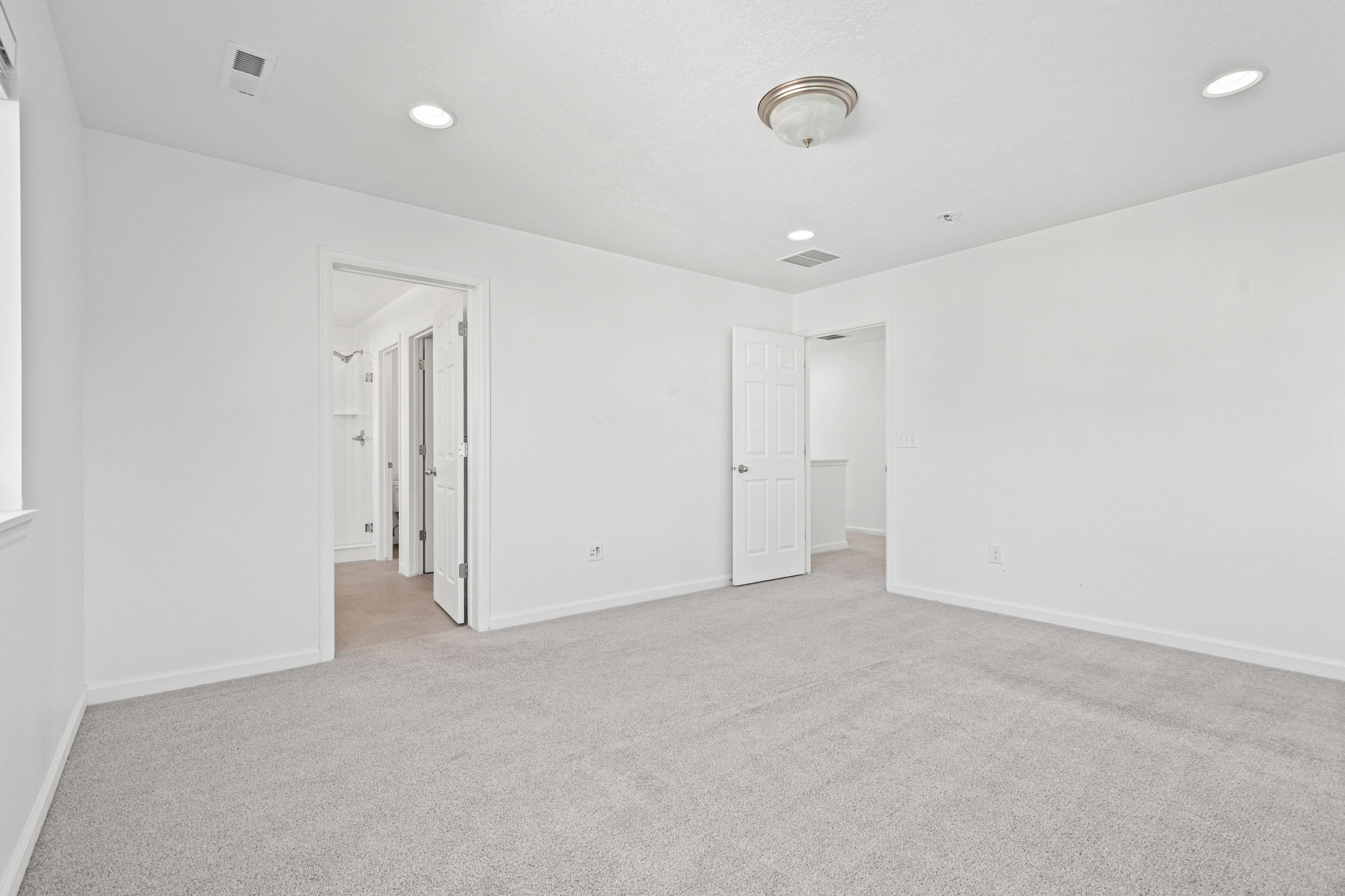 Carpeted room featuring white walls, recessed lighting, and a ceiling-mounted light fixture
