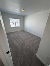 Spare room with dark colored carpet and a textured ceiling