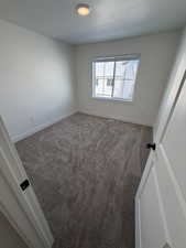 Unfurnished room with dark carpet and baseboards