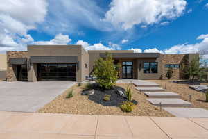 Southwest-style home with stone siding, stucco siding, a garage, and driveway