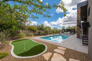 View of swimming pool with patio surround, a putting green, and a fenced backyard