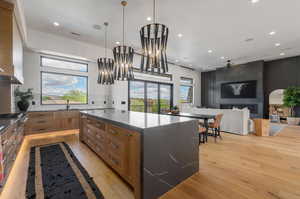 Kitchen with dark stone counters, a spacious island, open floor plan, light wood finished floors, and decorative backsplash