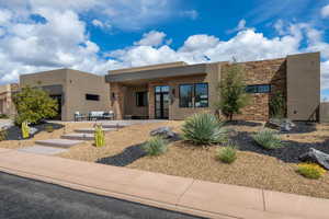 View of front of house featuring stucco siding and a patio